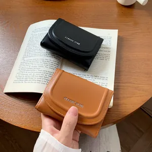 Porte-monnaie Classic Star en cuir noir et marron sur un bureau avec des livres anciens
