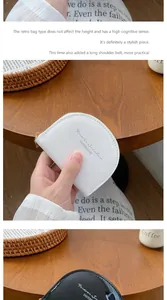 Dettaglio di un borsellino a semicerchio in pelle verniciata con zip e scritte stampate