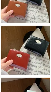 Detail of oil wax leather wallet with oval metal S logo and zipper closure