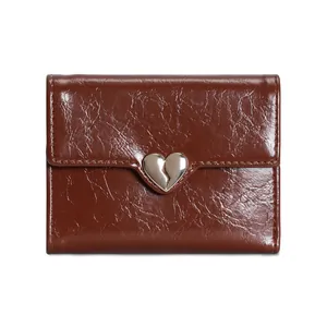 Detail of dark brown heart-shaped wallet with polished oil wax leather texture