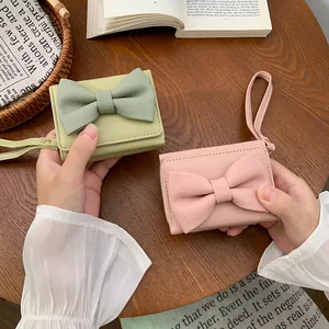 Mini portafogli con fiocco decorativo nei colori rosa e verde su un tavolo di legno