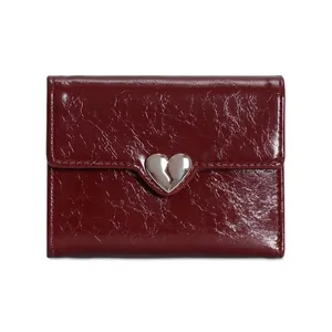 Detail of dark red glossy leather wallet with silver metal heart clasp and fine texture