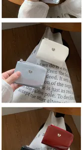 Détail de portefeuilles pliants à texture craquelée avec boucle cœur et fermeture éclair