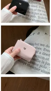 Détail du portefeuille à trois volets avec texture craquelée et logo cœur métallique