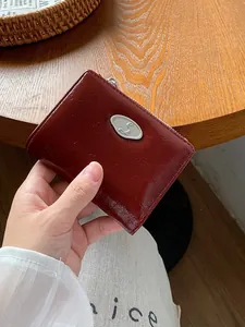 Burgundy minimalist wrinkled leather zip wallet with silver logo on wooden background