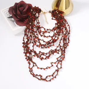 Multilayer bohemian beaded necklace with red and gold tones on a white aesthetic background
