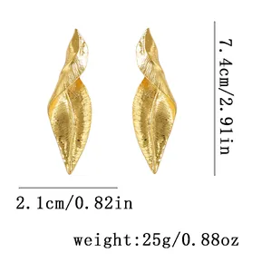 Dettaglio di grandi orecchini a foglia d'oro vintage con trama in metallo spazzolato