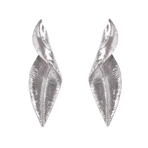 Dettaglio di orecchini a foglia d'argento con venature metalliche e trame intrecciate