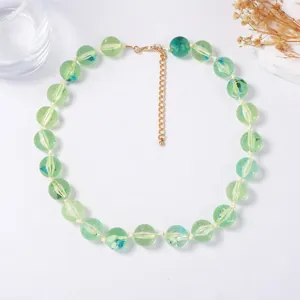 Détail du collier de perles en verre vert clair avec fermoir mousqueton doré brillant