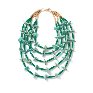 Detailopname van bohemian gelaagde kralenketting met groene steentextuur en goud
