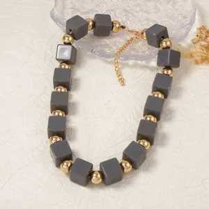 Détail du collier bohème montrant des perles carrées grises et un fermoir doré