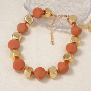 Macro-detail van beige matte kralen en gouden geometrische bedels op de ketting