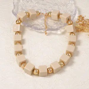 Détail de perles carrées crème et sphères dorées avec fermoir mousqueton robuste