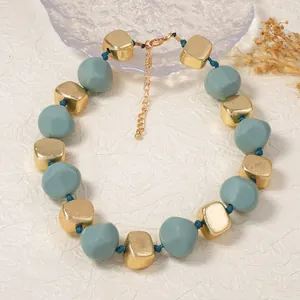 Minimalistische geometrische kralenketting met gouden vierkanten en blauwgrijze kralen