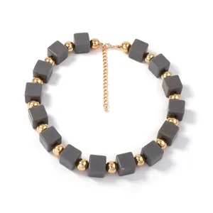 Collier bohème multicouche avec perles géométriques grises et détails dorés brillants