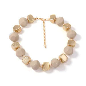 Detail van de kralenketting met beige harskralen en gouden getextureerde kralen