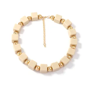 Détail d'un collier bohème fait main avec cubes beiges mats et perles dorées