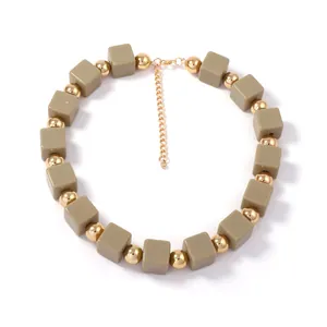 Détail de perles carrées kaki et billes dorées sur un collier bohème à plusieurs rangs