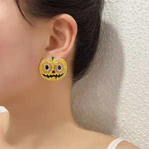 Orecchini a zucca di Halloween con strass arancioni e stelo verde indossati dal modello