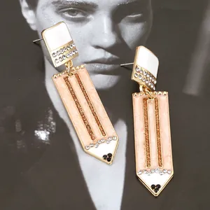 Detalle de pendientes de lápiz rosa con diamantes de imitación y aleación dorada fina