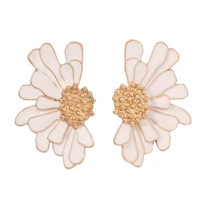 Détail de boucles d'oreilles marguerites en émail avec pétales crème et pistils dorés en macro