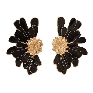 Détail de boucles d'oreilles fleurs en émail noir avec centre doré texturé