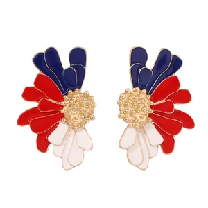 Détail macro de boucles d'oreilles fleurs en émail rouge blanc bleu avec cœur doré