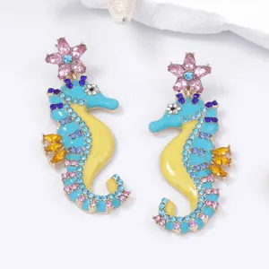 Detail of seahorse earrings with colorful enamel and sparkling rhinestones on white background