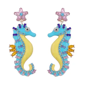 Close-up of seahorse drop earrings with pink star studs and colorful rhinestones