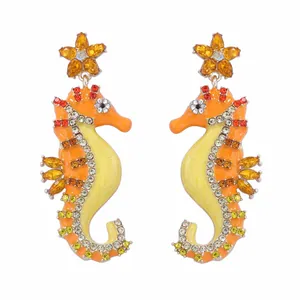 Macro detail of seahorse earrings with orange enamel and sparkling crystals
