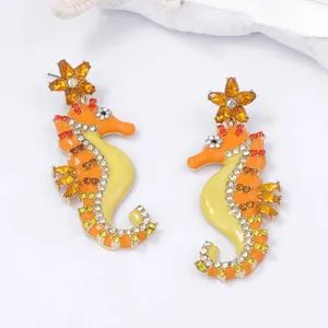 Vibrant seahorse drop earrings with orange enamel and sparkling crystals in 45-degree view