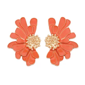 Détail macro de boucles d'oreilles fleurs en émail orange avec pétales dorés et perles