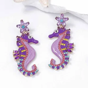 Macro shot of colorful rhinestone seahorse earrings with purple enamel flower studs