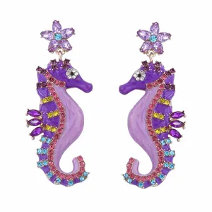 Elegant seahorse drop earrings with colorful crystals and floral stud on white background