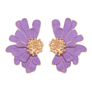 Détail macro de boucles d'oreilles fleurs en émail violet avec pétales dorés