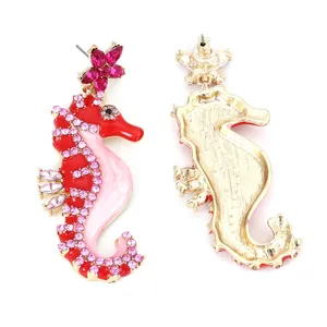 Detail of seahorse earrings with gold plating, red enamel, and pink rhinestones