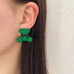 Orecchino a perno a forma di orso verde strutturato con fiocco nero indossato