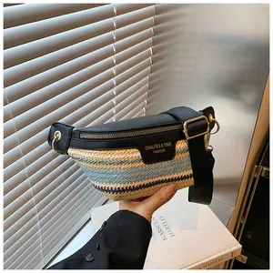Detail of woven straw and black leather crossbody bag with gold hardware and logo