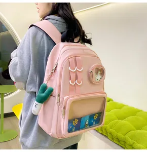 Modèle portant un sac à dos rose en nylon avec fenêtre PVC et breloque peluche