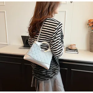 Détail d'un sac à main matelassé bleu clair avec poignée ronde et bandoulière chaîne argent