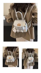 Dettaglio del mini zaino argento con ricamo a forma di cucciolo e ciondolo in peluche