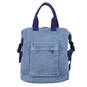 Detail of light blue denim backpack showing outer zip pocket and reinforced webbing handles