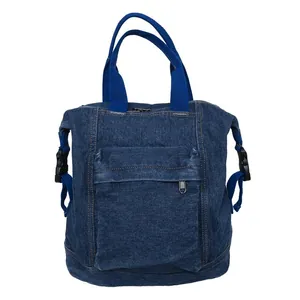 Detail of dark blue denim backpack featuring front zipper pocket and woven handles