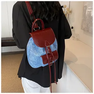 Fashionable denim and PU leather patchwork backpack with contrast buckles on model