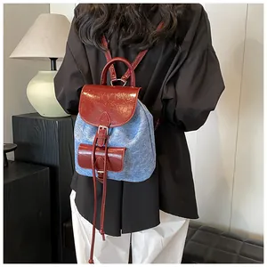 Model view of a red and blue patchwork denim backpack with glossy PU leather straps