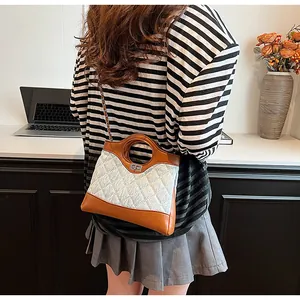 Détail du sac en denim matelassé bleu clair avec finitions en cuir brun et fermoir métal