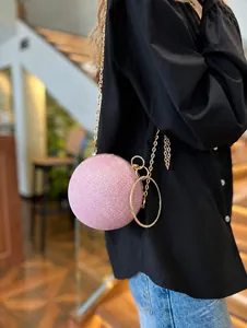Detail view of pink round evening bag with sparkling sequins and gold ring handle
