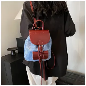 Rear view of a mini denim and red leather patchwork backpack worn by a model