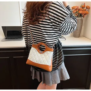 Détail du sac matelassé avec bordure en cuir marron et fermoir rotatif en métal