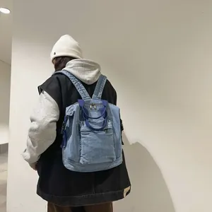 Detail view of the light blue denim backpack with dark blue woven handles and buckles